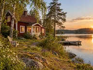 Rotes schwedisches Holzhaus am See mit Veranda und Steg – KI-generiertes Stimmungsbild